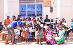 Gailey Mwesigwa handing out boxes of milk to those families in need